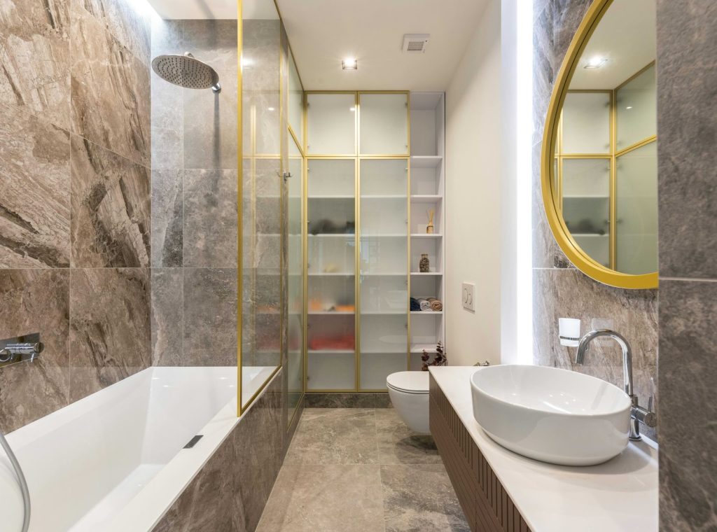 Bathroom with stone-look tile and gold fixtures