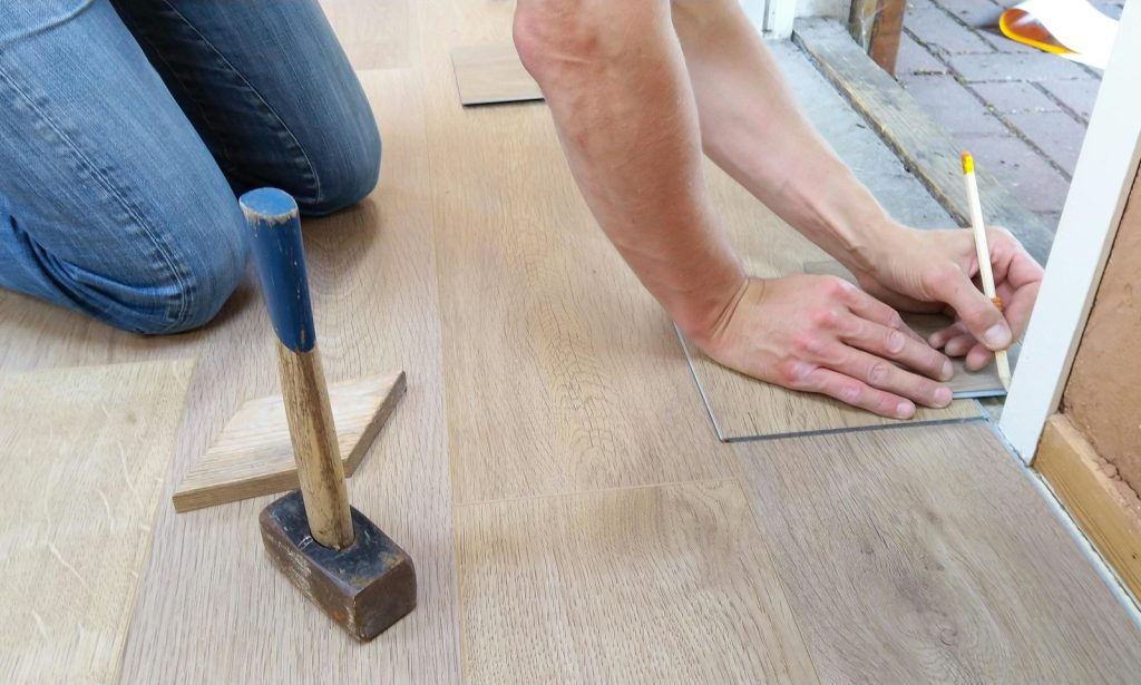 An installer measuring a hardwood plank